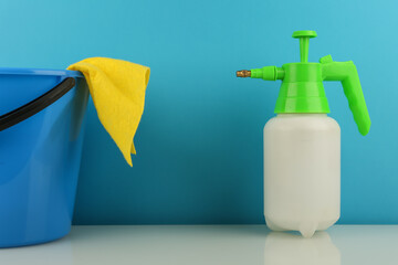 cleaning concept. spray bottle, bucket and rag on blue background