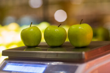 Closeup of three apples lying on weight scale.  Blurred background. Selective focus.