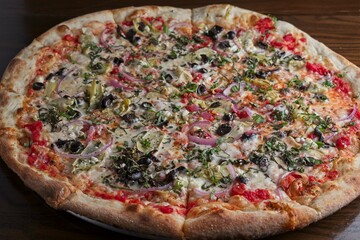 Gourmet pizza with fresh basil, feta cheese, artichoke, black olive & red onion