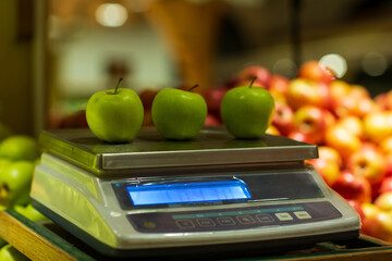 Closeup of three apples lying on weight scale.  Blurred background. Selective focus.