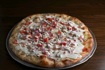 Gourmet pizza white pie with chicken, bacon, red onion and diced tomato. Drizzled with ranch