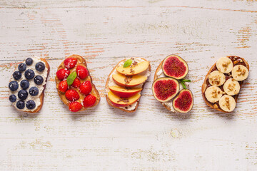 Homemade summer toast with cream cheese, nut butter and fruits and berries