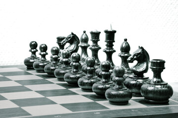 Black chess pieces on the board on white background. Start position of chess pieces. Black and white photo.