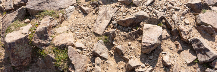 Panoramic image of the surface covered with big stones on the ground. The surface of the hiking trail. Top view