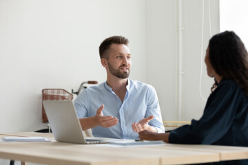 Obraz premium Diverse colleagues discussing project strategy, working on project together, sitting at table in modern office, African American businesswoman and Caucasian businessman brainstorming, sharing ideas