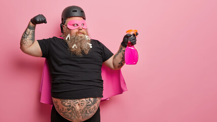 Horizontal shot of powerful superhero shows muscles and holds detergent or household supplies ready...