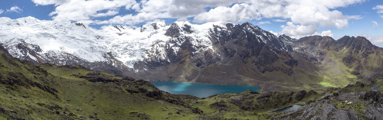 Naklejka na ściany i meble Panorama landscape of huge green mountains with snow and ice and a lake with blue sky and clouds, in cordilera Huaytapallana, Huancayo, peru