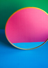 single round mirror  on green and blue background and pink and blue reflection in the mirror. color block mock up