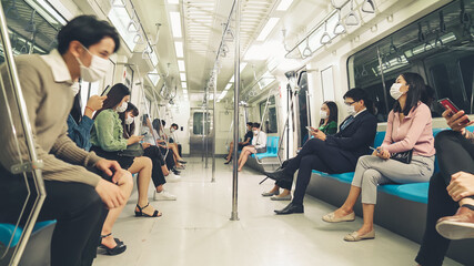 Crowd of people wearing face mask on a crowded public subway train travel . Coronavirus disease or COVID 19 pandemic outbreak and urban lifestyle problem in rush hour concept .