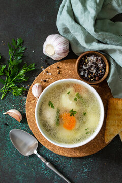 Chicken soup with vegetables on a dark stone table top. Top view flat lay background.