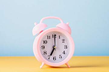 Pink alarm clock on a colored background