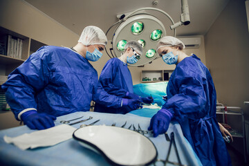 Portrait of team of surgeons at work. Three doctors in medical masks in operations begin to operate...