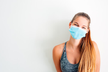 portrait of a girl in sportswear wearing a protective mask against covid virus with positive...