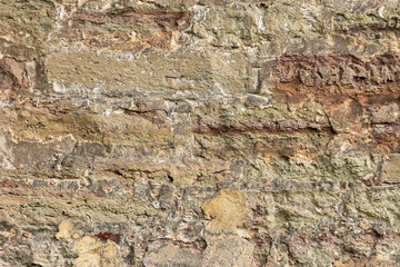 The surface of an old stone wall, masonry of uneven wild hewn stones.