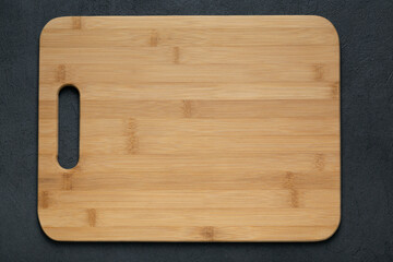 Rustic wooden cutting board on dark table top view copy space