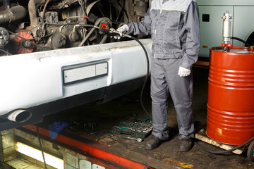 The mechanic drains the old oil from the engine