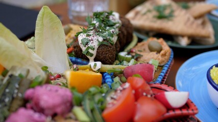 Middle eastern healthy vegan appetizer plate of falafels, hummus, pickles, baba ghanoush and assorted dips. Meze in vegan style