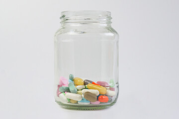 Assorted pharmaceutical medicine pills in a Transparent jar with white background.