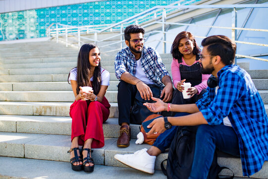 indian friends sitting on stairs outdoors with copybooks