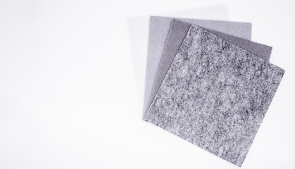 Five square pieces of felt of different shades of gray from dark to very light, isolated. Grey spectrum. Copy space