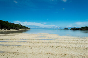 遠浅の白い砂紋のある海岸と快晴の空