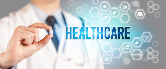 Close-up of a doctor giving you a pill with HEALTHCARE inscription, medical concept