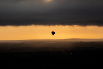 In the low sun of the morning a balloon gets close to the cloud cover 