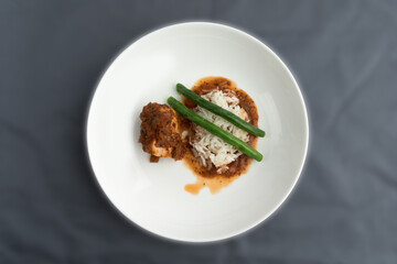 a dinner of chicken with salsa or chicken cacciatore in an elegant  white bowl on a blue table