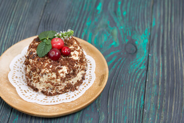 Sponge cake with butter cream. Decorated with cranberries and mint. Against the background of brushed pine boards.