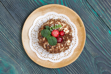 Sponge cake with butter cream. Decorated with cranberries and mint. Against the background of brushed pine boards.