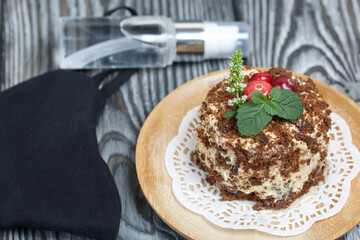 Sponge cake with butter cream. Decorated with cranberries and mint. Nearby is a protective mask and antiseptic. Against the background of brushed pine boards.