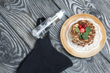 Sponge cake with butter cream. Decorated with cranberries and mint. Nearby is a protective mask and antiseptic. Against the background of brushed pine boards.