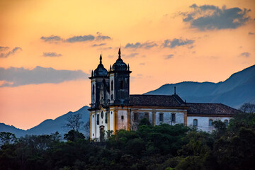 Ancient and historic church on top of the hill during sunset in the city of Ouro Preto in Minas Gerais, Brazil with the mountains behind