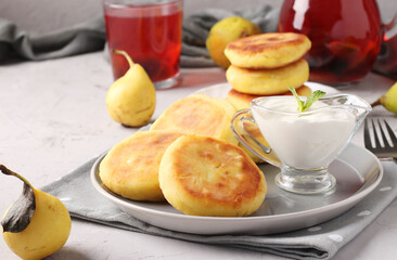 Traditional Ukrainian dish syrniki with berry jam and sour cream on grey plate on light background, Closeup