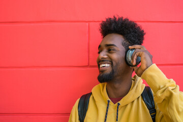 Young afro man listening to music with headphones.