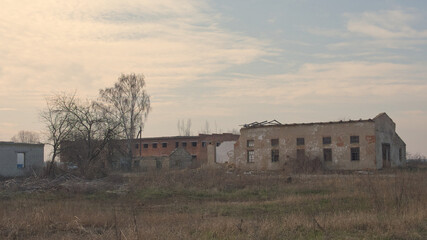 Fototapeta na wymiar An abandoned industrial building at a farm enterprise in Ukraine. Evening landscape.
