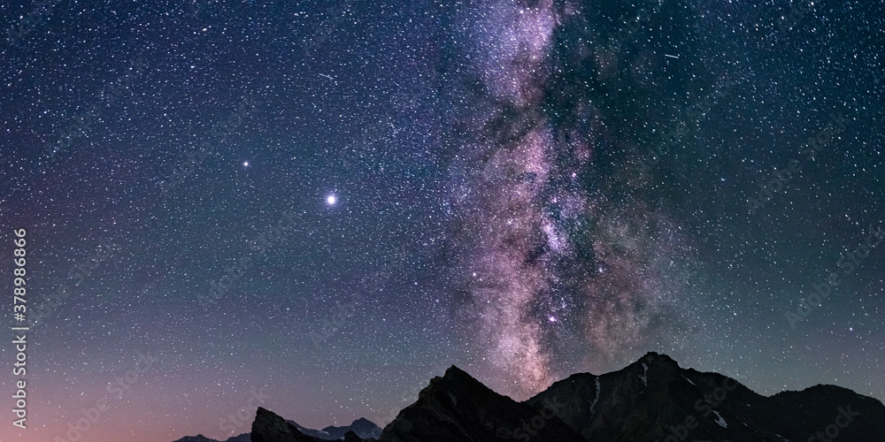 Wall mural the milky way core and glowing stars in the night sky oover the alps. panoramic view high mountain r