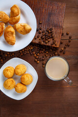 A transparent mug with coffee with cream and a jug of cream and croissants on the table among the scattered coffee beans.