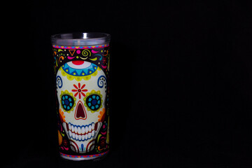 a hand painted day of the dead skull candle on a black background