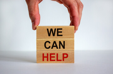 Male hand placing a block with word 'we' on top of a blocks tower with words 'we can help'. White...