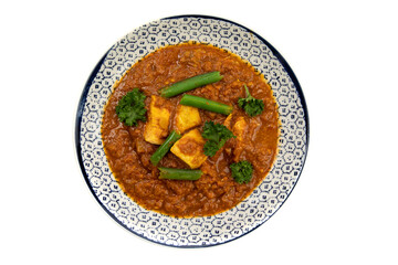 overhead view of a blue bowl of Indian buttered chicken on a white background