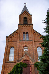 
The majestic red brick church of St. John the Baptist in the village of Opsa, Belarus. The facade of the church on a cloudy day.