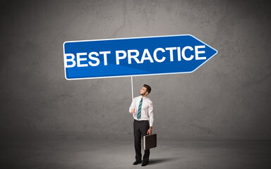 Young business person in casual holding road sign with BEST PRACTICE inscription, new business direction concept