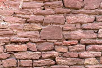 Old stone wall for the backdrop. Color - brown, shade of red. Boulders of irregular shape. Concept of an antique or medieval wall.