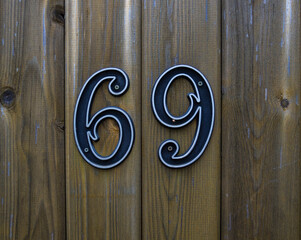 Bronze house number sixty nine 69 on a wooden door
