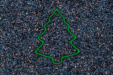 black rice background with christmas tree cookie cutter, x-mas concept
