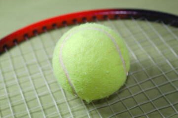 Tennis racket with ball on a green background