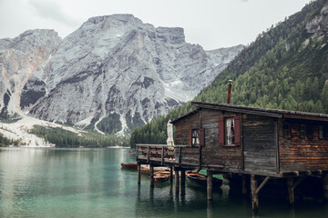 Wooden house, big mountains and blue lake in Lago di Braies, Dolomites Alps, Italy