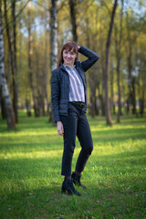 Young girl in trousers and a jacket posing in a spring park.