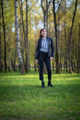 Young girl in trousers and a jacket posing in a spring park.